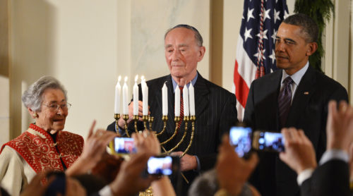 U.S. President Obama watches as a Holocaust survivor lights the candles of the menorah during a Hanukkah reception in Washington