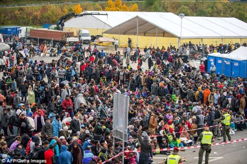 Influx: More than 12,000 migrants (pictured waiting for a bus after crossing the Slovenia-Austria border) have streamed into the country in the last 24 hours.