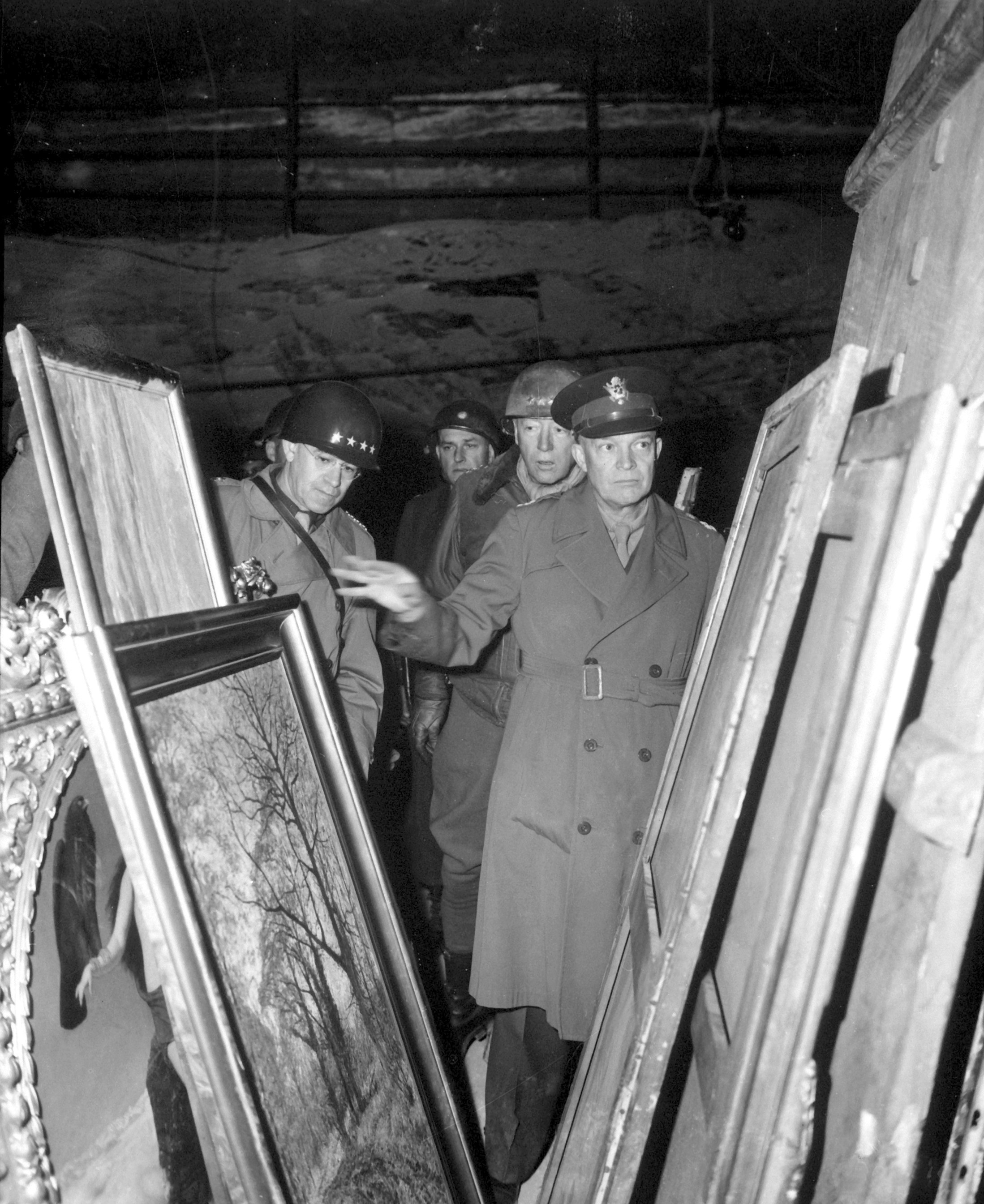 U.S General Dwight D. Eisenhower, Supreme Allied Commander, accompanied by General Omar N. Bradley and Lieutenant General George S. Patton, Jr., inspects art treasures secured from Allied air attacks by their being hidden in a salt mine in Germany. These artworks were looted and shipped to the United States where many are still illegally stored.