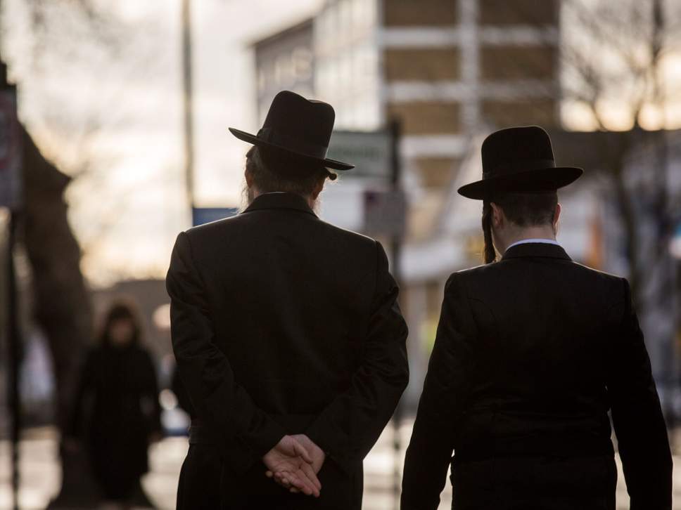 Jewish men walk along the street in Stamford Hill. 